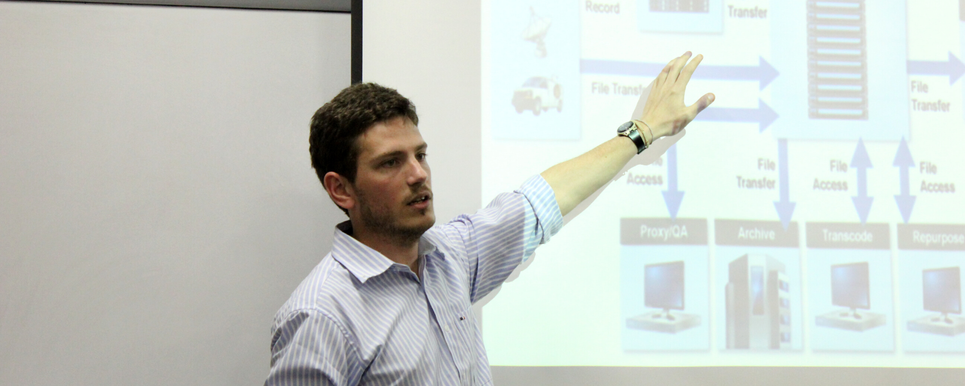 Juan Brenes muestra el contenido de una diapositiva durante una presentación en la UM.