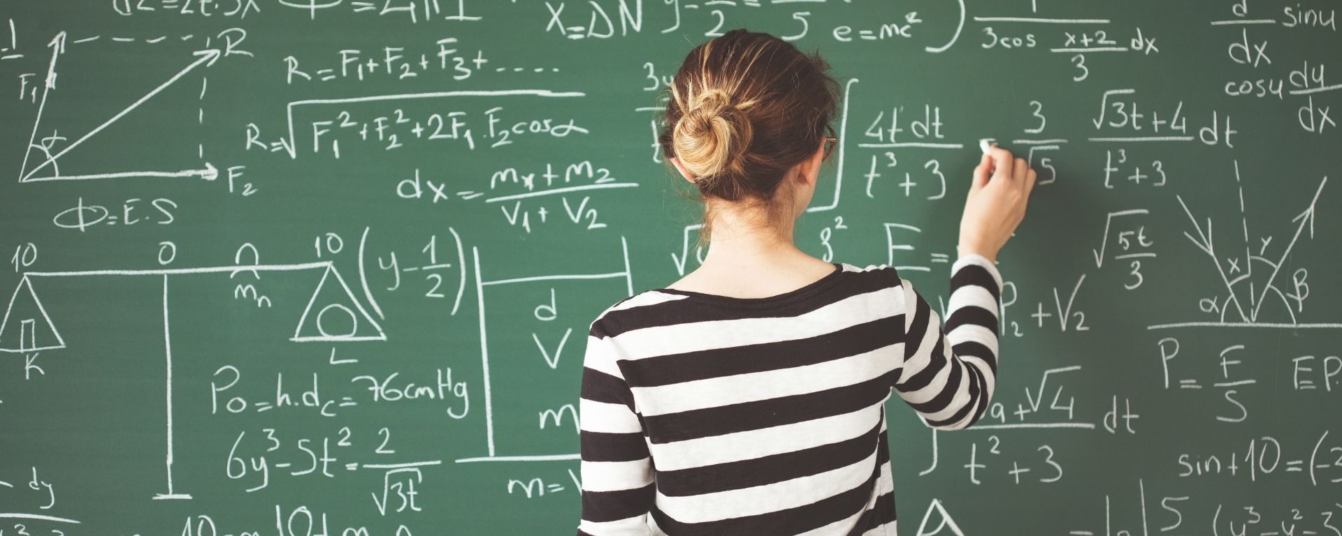 Chica de espaldas escribiendo en un pizarrón Chica de espaldas escribiendo en un pizarrón