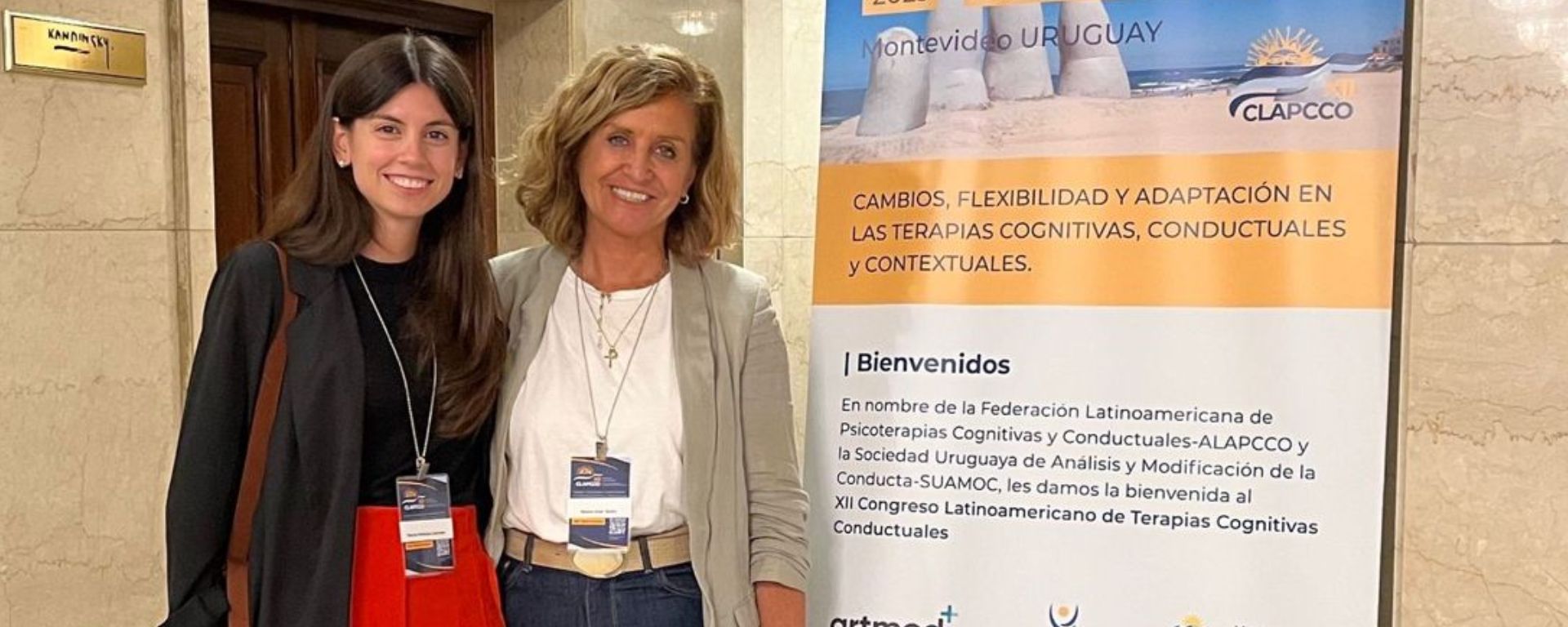Mónica Larrosa y María José Soler posan con afiche del XII Congreso Latinoamericano de Terapias Cognitivas