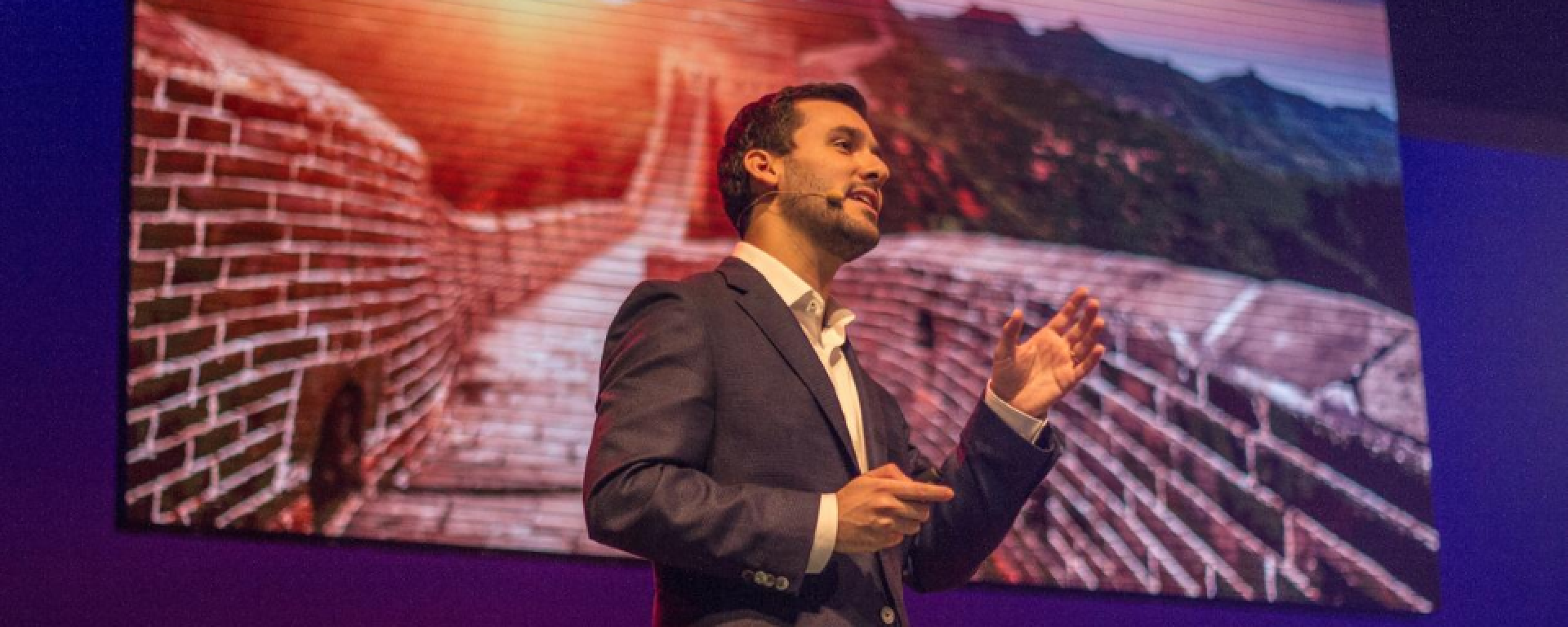 Nicolás Santo durante una charla TEDx con la imagen de la Gran Muralla china detrás.