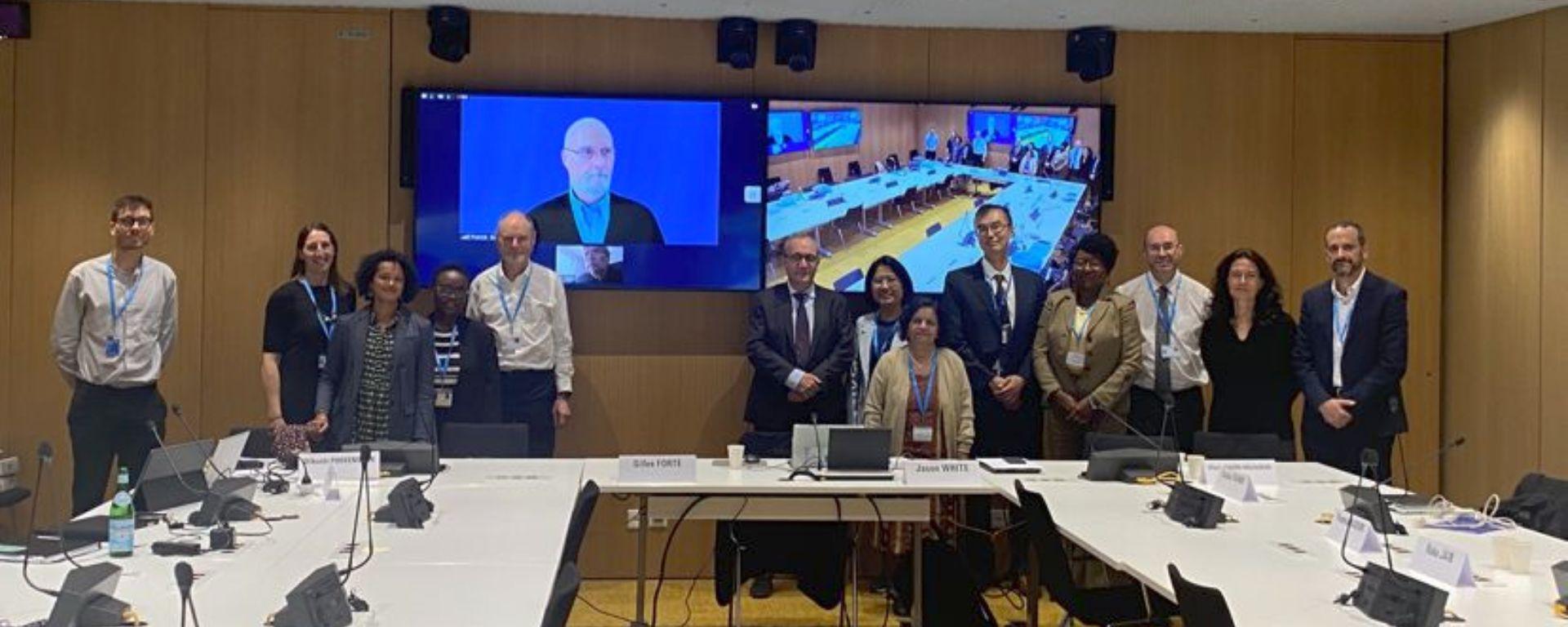 Antonio Pascale posa junto a comité de expertos en Farmacodependencia de la OMS, en mesa en "u", con pantallas digitales de fondo